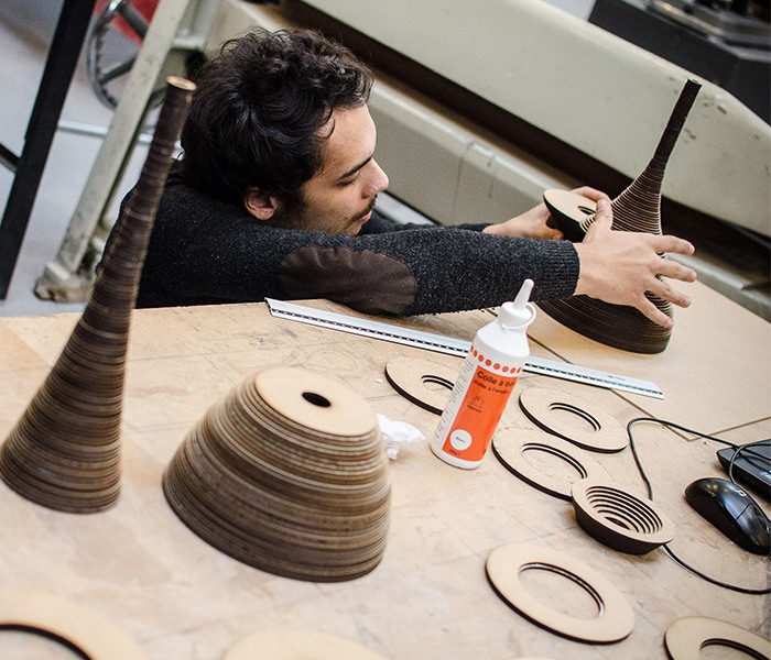 Étudiant en design à l'École Bleue travaillant sur un prototype en bois découpé