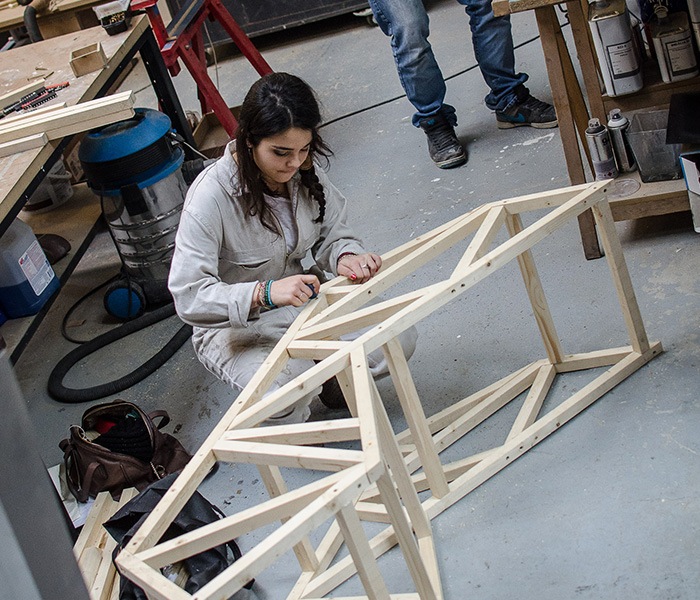 Étudiante École Bleue construisant une structure en bois dans un atelier