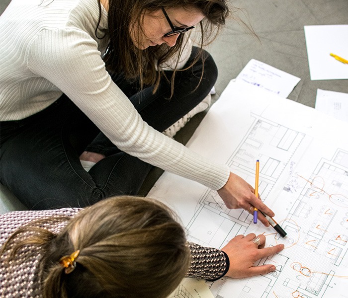 Étudiantes en école d'architecture intérieure travaillant au sol sur des plans