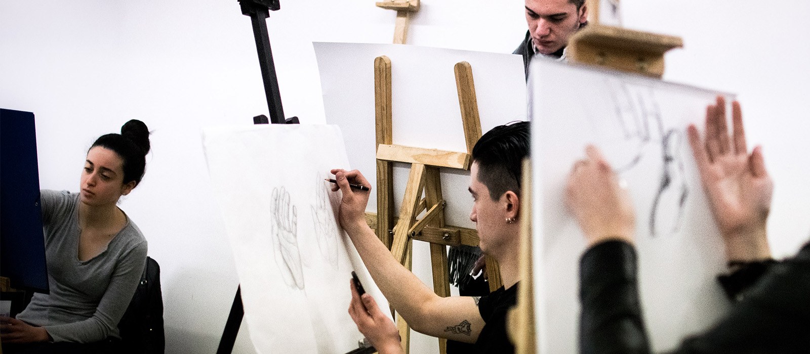 Étudiants en école de design dessinant des mains sur des chevalets en atelier